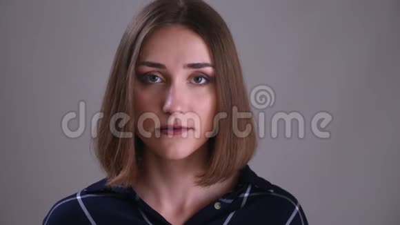 特写镜头年轻漂亮的短头发的女性脸看着镜头背景隔离在灰色视频的预览图