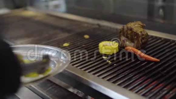 专业厨师在餐厅厨房的烤架上烹饪蔬菜特写镜头把肉放在盘子里煮视频的预览图