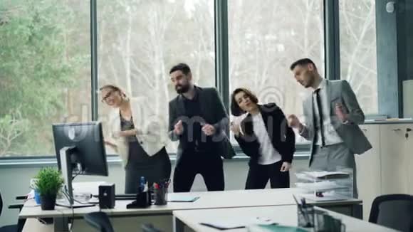 一群快乐无忧无虑的同事在办公室里跳舞在聚会上庆祝公司的活动笑着玩着视频的预览图