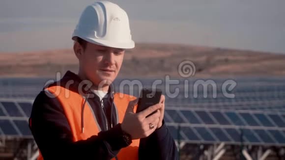 一位穿着橙色背心的工程师通过电话向他的上级报告了企业太阳能电池板的状况视频的预览图