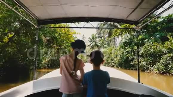 小女孩和小男孩一起乘着旅行船沿着奇异的丛林河流航行年轻的探险者在荒野中视频的预览图