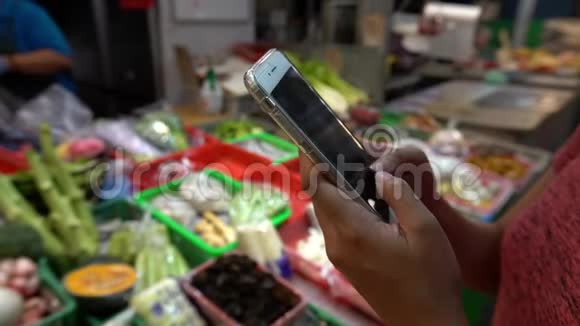 4K亚洲女性手持触摸屏智能手机在传统市场视频的预览图