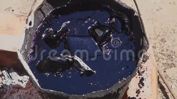 砖上一桶沸腾的树脂沥青片用煤气燃烧器在桶中熔化屋顶修理视频的预览图