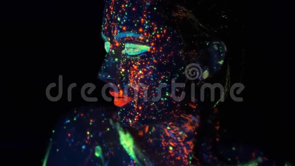 霓虹灯画在女孩脸上一位年轻女子的肖像画上了发光的油漆视频的预览图
