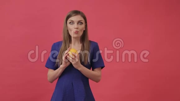 一个美丽的女孩穿着一件连着耳机和一个橘子然后跳舞和听音乐紫色工作室视频的预览图