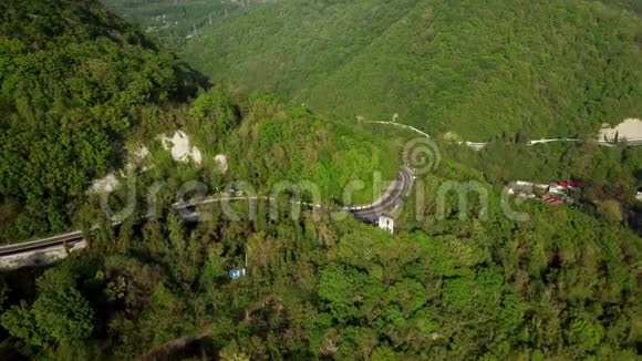 一条弯弯曲曲的公路在群山与绿树之间的空中俯瞰视频的预览图