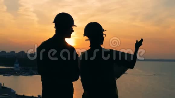 工人谈话站在夕阳背景下后景视频的预览图