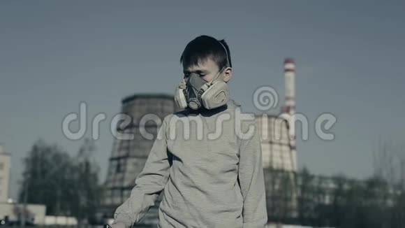 年轻男孩戴着呼吸器用手机对抗工厂烟囱空气污染概念切尔诺贝利视频的预览图