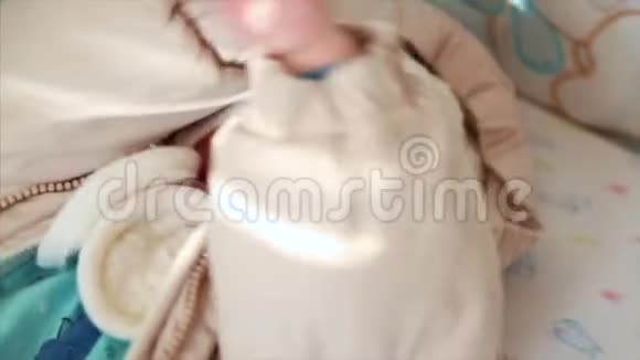 在阳光明媚的卧室里穿着针织衣服的可爱的小宝宝视频的预览图