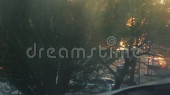 离焦城市交通灯日落时分的模糊画面小雨把水滴落在窗户上汽车开动起来视频的预览图