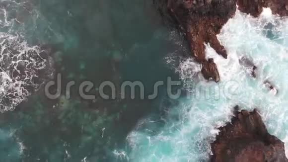 在西班牙的特内里费大西洋海岸上空升起了一架无人驾驶飞机水晶般清澈的水洗过的岩石视频的预览图