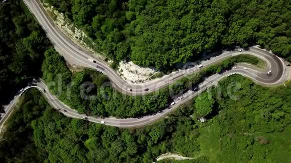 空中飞过一条弯曲的蜿蜒的道路用汽车和卡车穿过群山视频的预览图