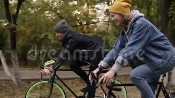 微笑年轻的时髦夫妇享受骑自行车通过公园徒步自行车两个戴帽子的年轻人视频的预览图