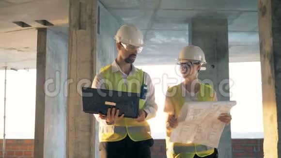 工人们走在一栋大楼里看着一台笔记本电脑关门视频的预览图