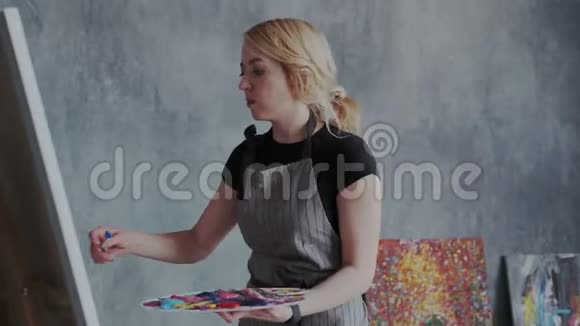 绘画过程才华横溢的熟练金发女画家在画布上用丙烯酸颜料创作现代抽象形象她是视频的预览图
