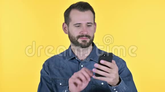 使用智能手机的胡子年轻人黄色背景视频的预览图