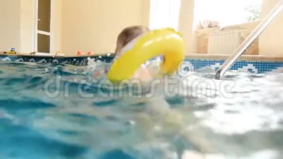带充气环的微笑幼儿球在游泳池游泳的4k镜头幼儿游泳视频的预览图