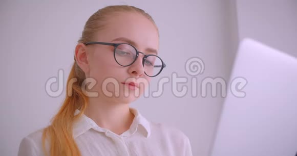 戴着眼镜的年轻漂亮白种人金发女商人的特写照片她用笔记本电脑笑得开心视频的预览图