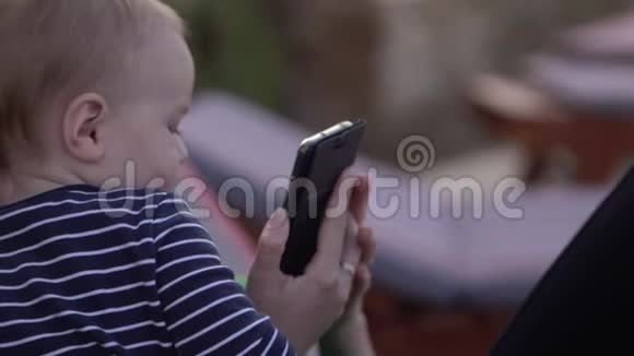 婴儿正坐在母亲旁边母亲缓慢地握住智能手机视频的预览图