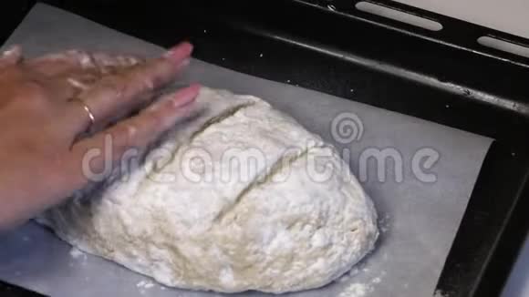烤片上有一块用面粉做的面团就像一条带切的面包女人的手在给视频的预览图