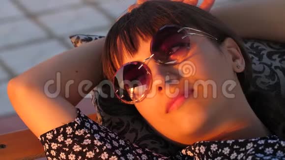 太阳眼镜的女人在日落时休息视频的预览图