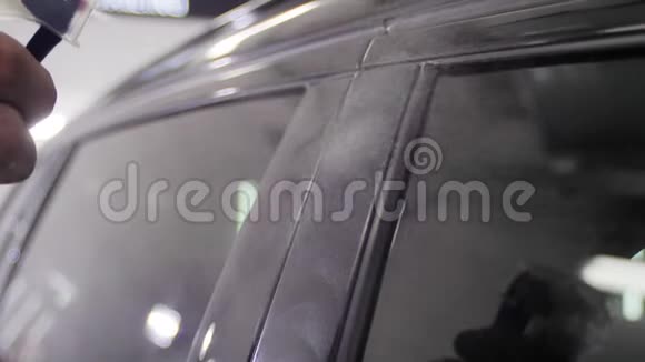 在一家汽车服务站里一位手工工人正在用一种特殊的打蜡设备抛光一个黑色的汽车门架4慢视频的预览图