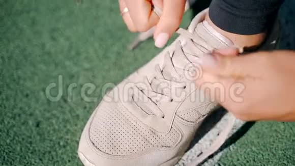 一个年轻女孩在街上的运动场上系着米色运动鞋的花边特写镜头视频的预览图