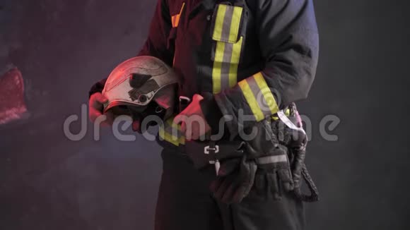 一名穿着特殊制服的勇敢消防员手持防护头盔站在灰色的墙壁上视频的预览图