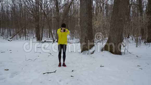 穿黄色外套的运动员在自由空间的冬季森林里跳绳视频的预览图