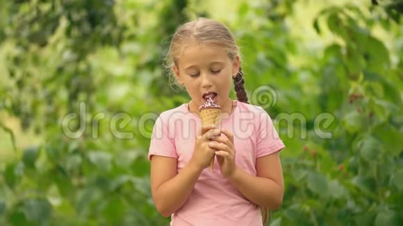 在绿色树叶背景下吃冰淇淋的女孩视频的预览图