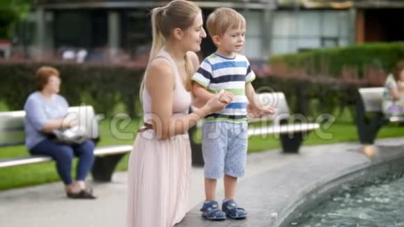 小托德勒男孩在公园的高墙上行走时手牵着母亲的4K镜头视频的预览图