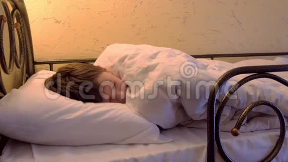 男孩睡在铺床上的旅舍里醒来伸展和打哈欠视频的预览图