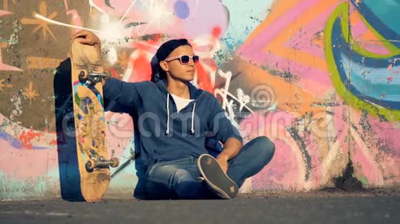 街头艺术墙有一个十几岁的溜冰者坐着靠在墙上视频的预览图