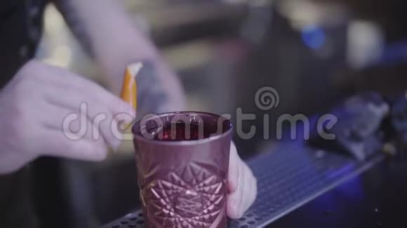不可辨认的年轻酒保在给客人上酒之前用橘子皮擦了一杯粘土鸡尾酒夜晚视频的预览图