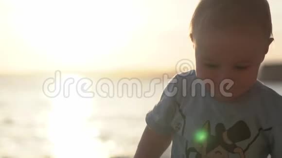 小可爱的宝宝在日落时慢悠悠地走在海边视频的预览图