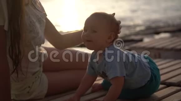 女孩在傍晚的海滩上缓慢地抚摸着小婴儿的头视频的预览图