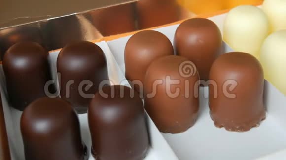一个半空的盒子里面有白巧克力黑巧克力和牛奶巧克力做成的糖果状的松饼甜点视频的预览图