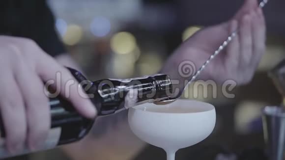 酒精手把红色的液体从瓶子倒入长勺放入白色漂亮的鸡尾酒杯视频的预览图
