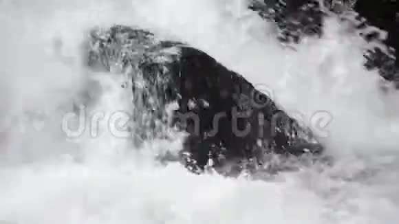 水流向下流过悬崖和岩石靠近瀑布附近的小溪里泼水清澈的河水视频的预览图