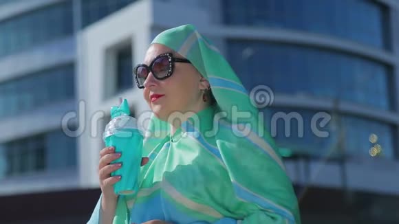 一位年轻的穆斯林妇女戴着浅色围巾和太阳镜背景是现代建筑视频的预览图
