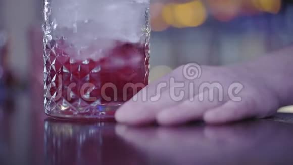 一杯冰块里面是红色饮料手放在吧台上在玻璃中混合液体视频的预览图
