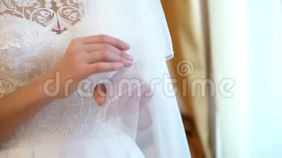 新娘费用特写镜头新娘用轻柔的指甲她的手在白色的背景下托着雪白的面纱视频的预览图