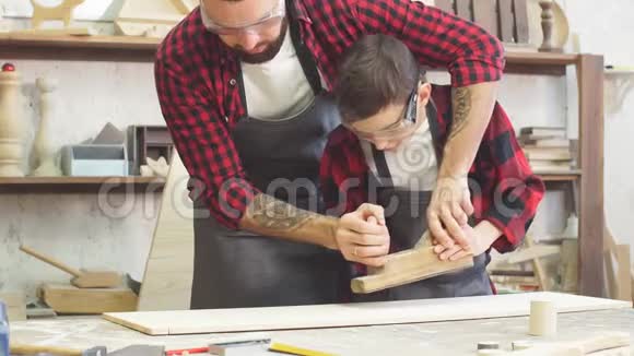 木匠看着他的小实习生在木桌旁和乔特一起工作视频的预览图