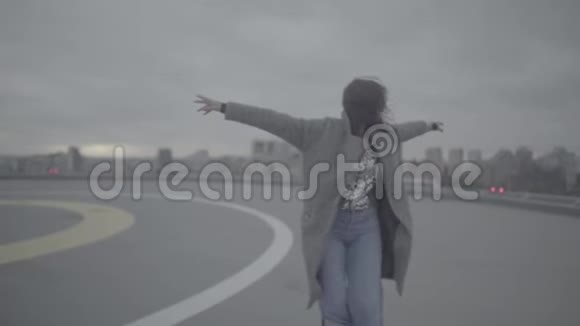 可爱的女孩双臂张开在刮风的天气里散步慢动作slog视频的预览图