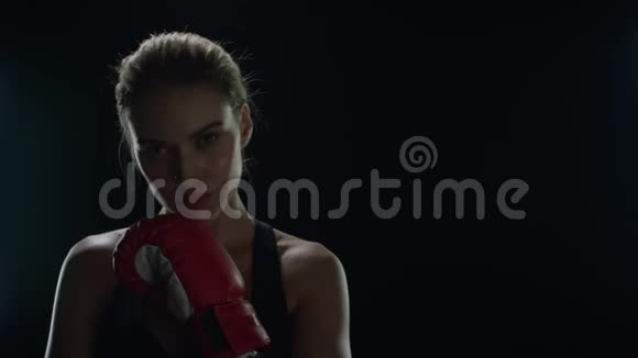 年轻女子戴着黑色背景的红色拳击手套视频的预览图