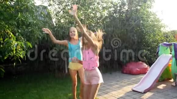 两个快乐的少女在夕阳下的夏雨中跳舞的慢镜头视频视频的预览图