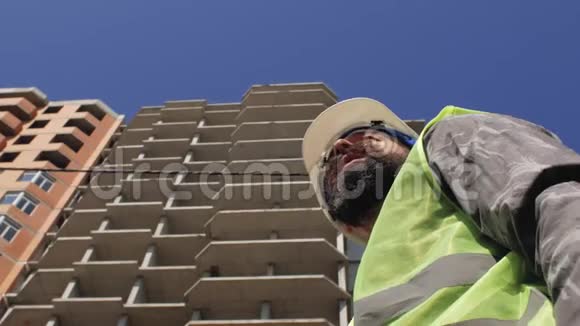 在建房屋背景下施工领班留胡子留胡子戴安全帽4k视频的预览图