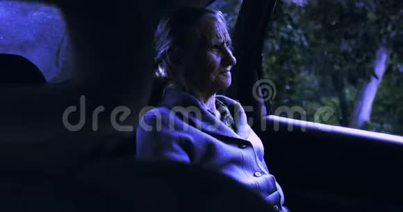 一位满脸皱纹的老妇人晚上坐在车里视频的预览图