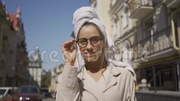 微笑的年轻女子的肖像头上戴着毛巾戴着眼镜站在街上看着镜头微笑视频的预览图