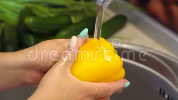 厨房里一个年轻女孩在家洗黄色的甜椒4K视频的预览图